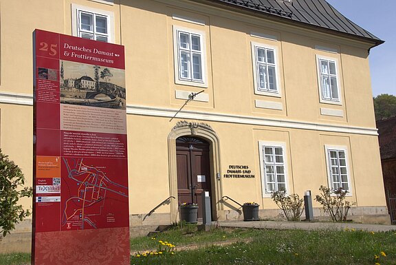 Deutsches Damast- und Frottiermuseum Großschönau im Vordergrund links steht die Säule des Textillehrpfades mit Erklärungen zum Kupferhaus, dem Deutschen Damast- und Frottiermuseum im Hintergrund