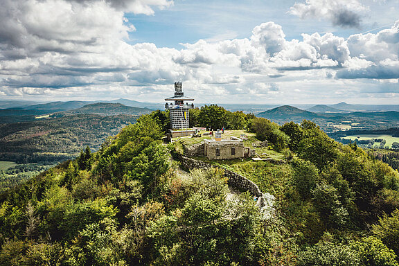 Auf der Lausche Luftbild zeigt die Lausche mit Turm, am Turm hängt die Oberlausitz-Fahne, am Horizont sind links Hochwald und Jeschken zu sehen, rechts drei Berge des Lausitzer Gebirges